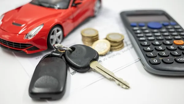 Calculadora ao lado de chave de carro e documentos representando custos automotivos