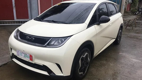 BYD Dolphin Mini estacionado em concessionária com clientes em background