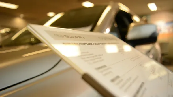 Concessionária de automóveis com placa indicando vendas e exposição de veículos