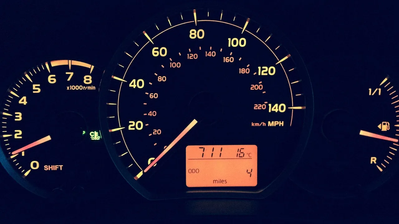 Painel de carro com hodômetro e velocímetro iluminados em ambiente escuro