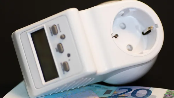 Carro elétrico conectado a tomada residencial com medidor de energia ao lado